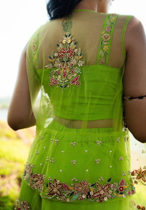 Back side of the green sharara set featuring a sheer net embroidered jacket over a sleeveless blouse.