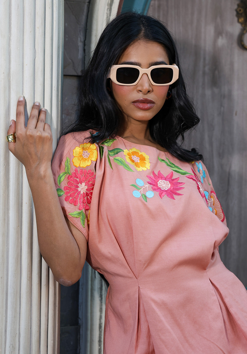 Close-up of peach embroidered top with colorful floral embroidery and pleated waist detailing