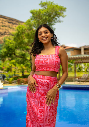 Model wearing a printed top and matching skirt near the poolside — a vibrant summer coord set.