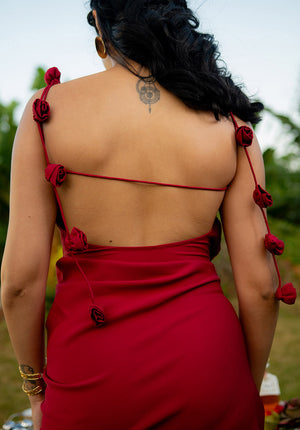 Close-up of the red backless dress featuring a single shoulder strap and rose embellishments, emphasizing the romantic design.