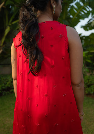 Back view of red lehenga with embellished cape detailing, highlighting craftsmanship and design.