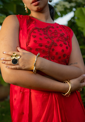 Sleeveless red lehenga blouse with round neckline, styled with rings and bangles for a chic ethnic touch.