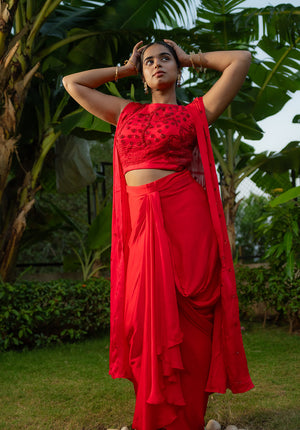 Model wearing red lehenga set with matching blouse and skirt, styled with bangles for a festive look.
