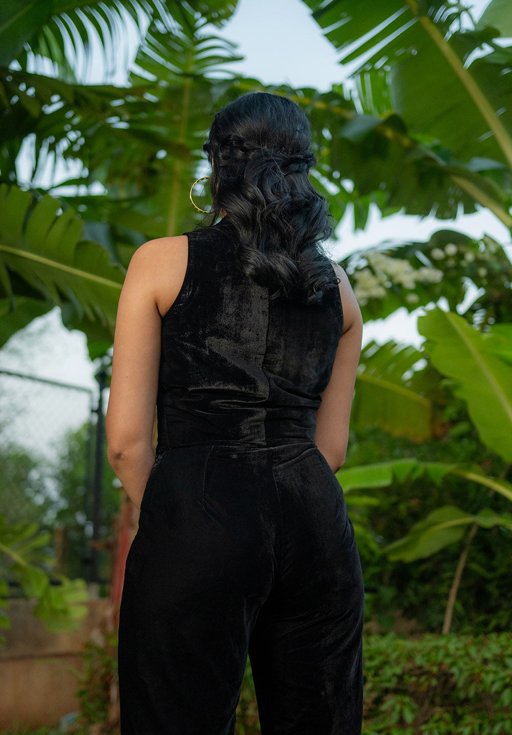 Back pose of the model in a black co-ord set, standing in the garden