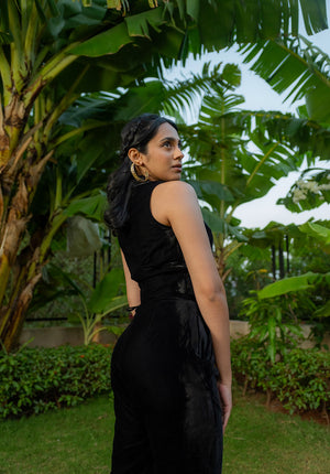 Model wearing plain black co-ord set amidst lush greenery
