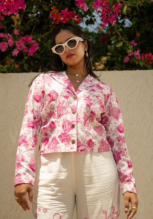 Close-up of blazer with white and pink print, showing collar and plackets; model wears sunglasses