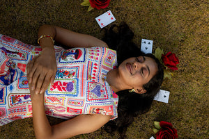 Close-up of model lying on the floor in a co-ord set with cards print