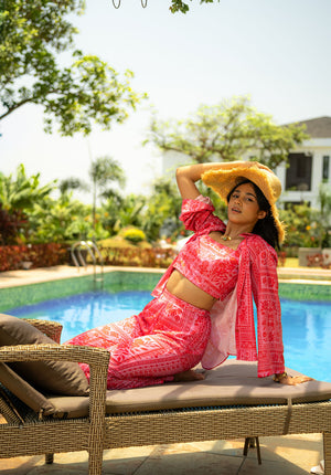 Model sitting on a bench near the pool wearing a hat and printed co-ord set