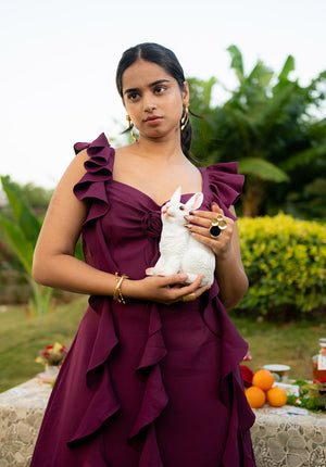 Model wearing a purple dress and holding a rabbit, captured in a natural outdoor setting