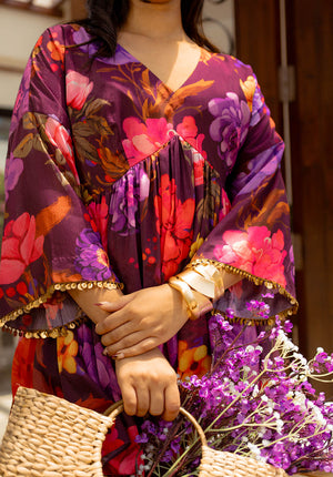 Close-up of a purple floral V-neck dress with gold trim on sleeves