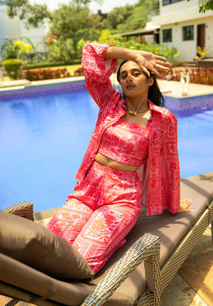 Model sitting near poolside in a shirt, top, and printed pants co-ord set