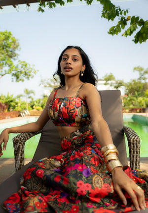 Model sitting on a chair wearing a sleeveless floral top