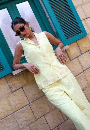 Close-up of pastel yellow sleeveless waistcoat with palm embroidery and statement buttons