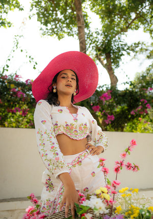 Model in white coord set with a pink hat, giving a standing pose — ideal for resort or day-out styling.