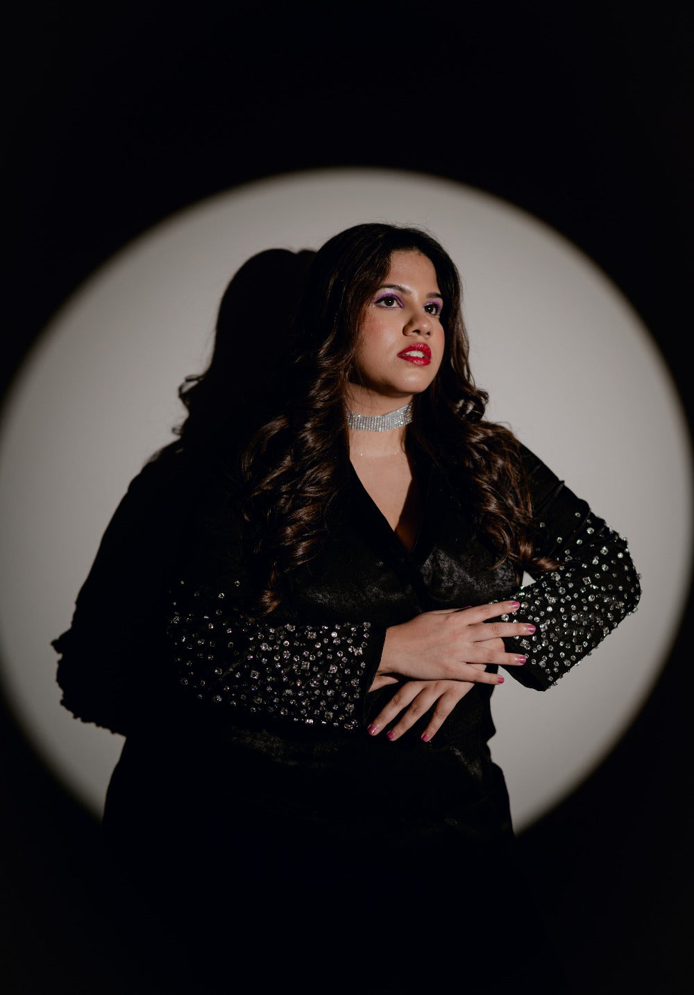Model wearing a black double-breasted blazer with crystal hand embroidery, posing with dramatic lighting.