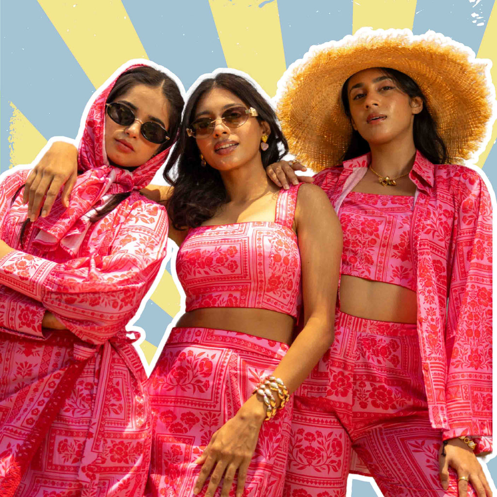 Three women wearing coordinated pink floral sets with statement accessories.
