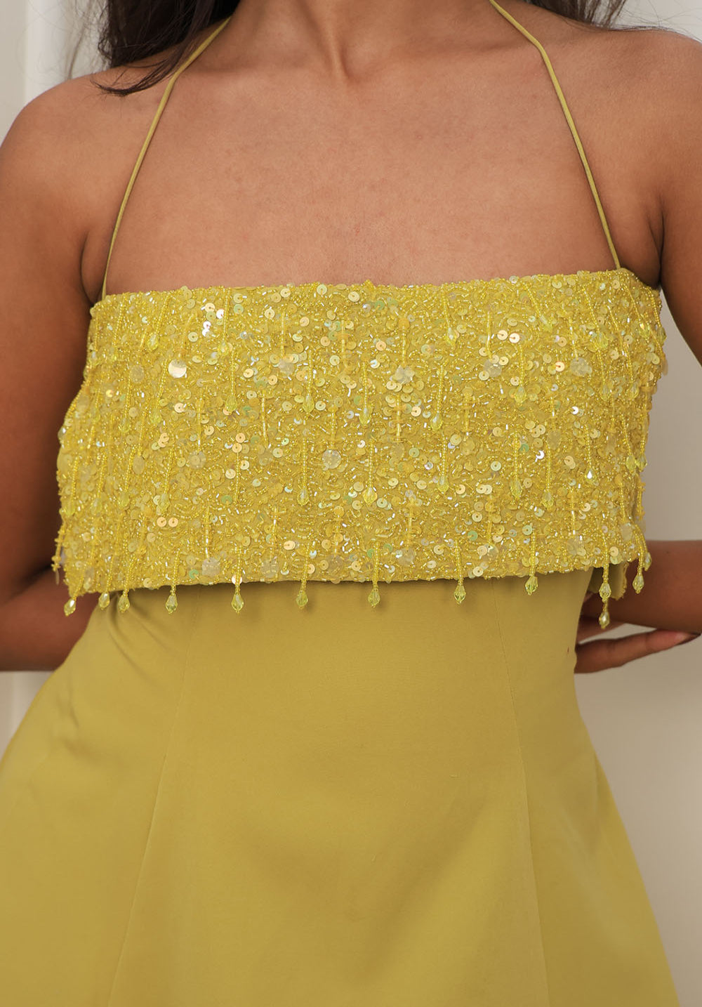 Close-up detail of hand-embellished sequin bodice on the Limoncello Halter Mini Dress in yellow.