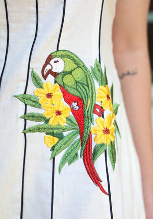 Detailed close-up of colorful parrot embroidery on the Parasio dress