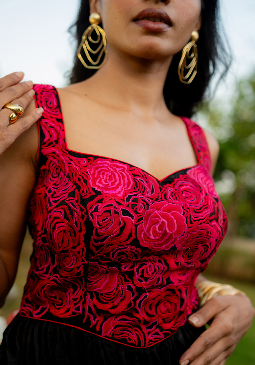 Close-up of the red rose embroidery on the bodice of the sleeveless black and red dress, showing intricate floral detailing.

