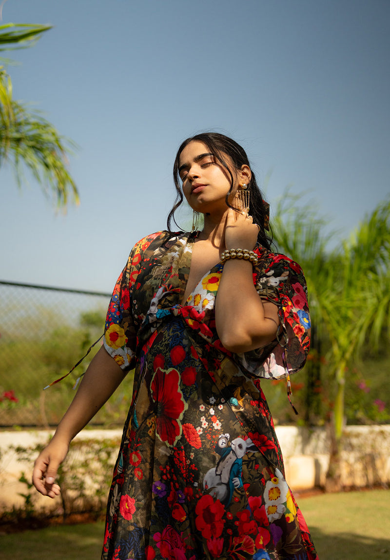 Model in a floral dress with drawstring sleeves, hand on neck, styled with golden bangles
