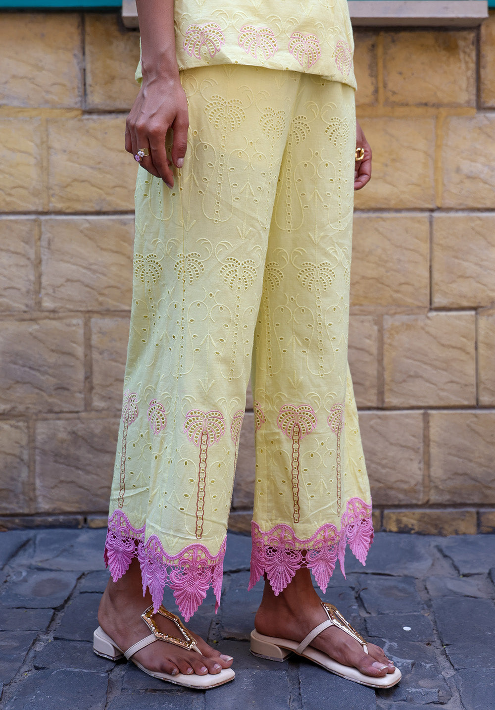 Close-up of pastel yellow palm embroidered fabric detailing on wide-leg pants