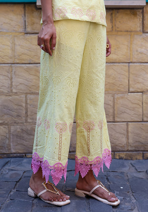 Close-up of pastel yellow palm embroidered fabric detailing on wide-leg pants